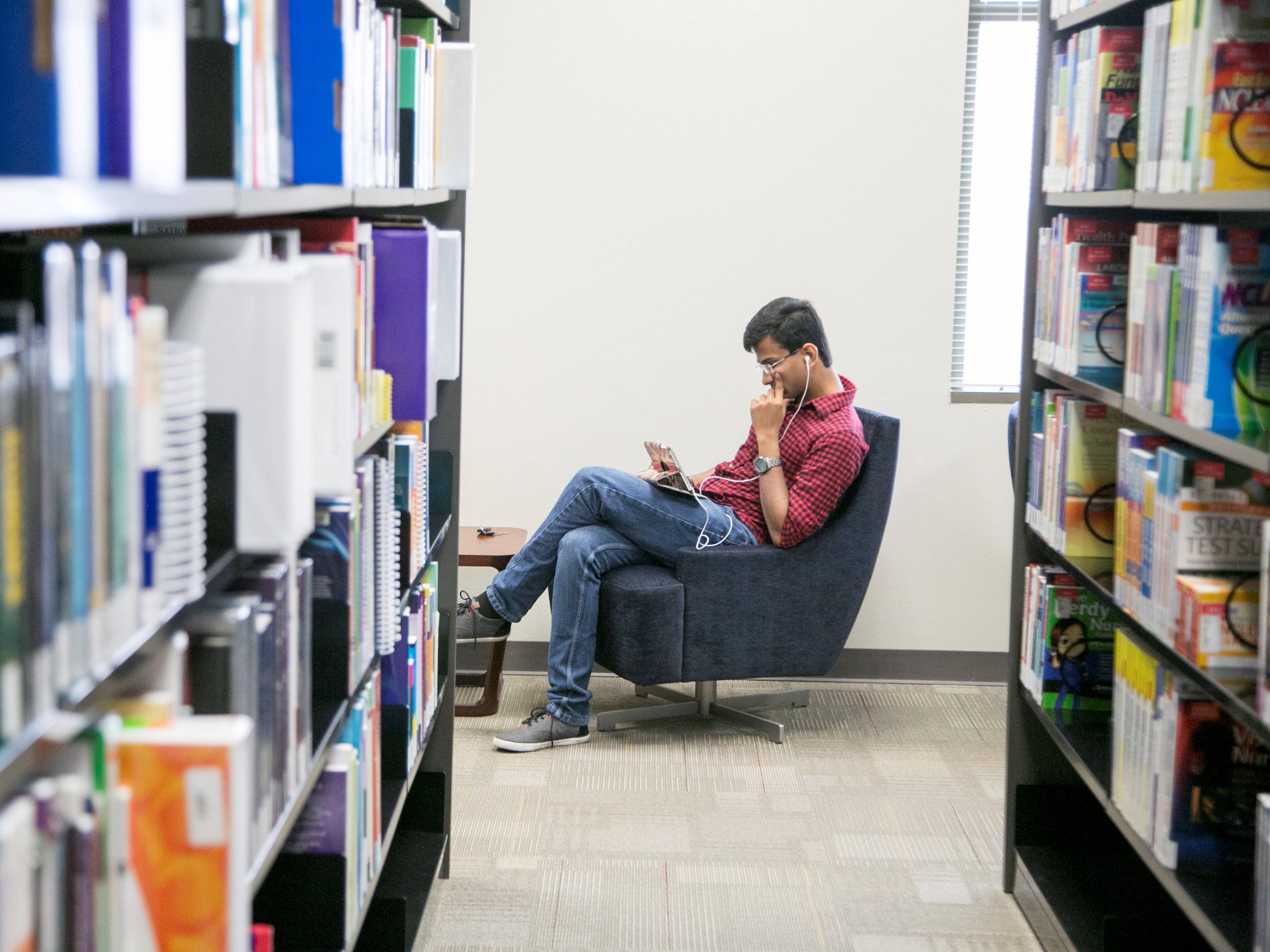 student reading a book at the round rock campus library