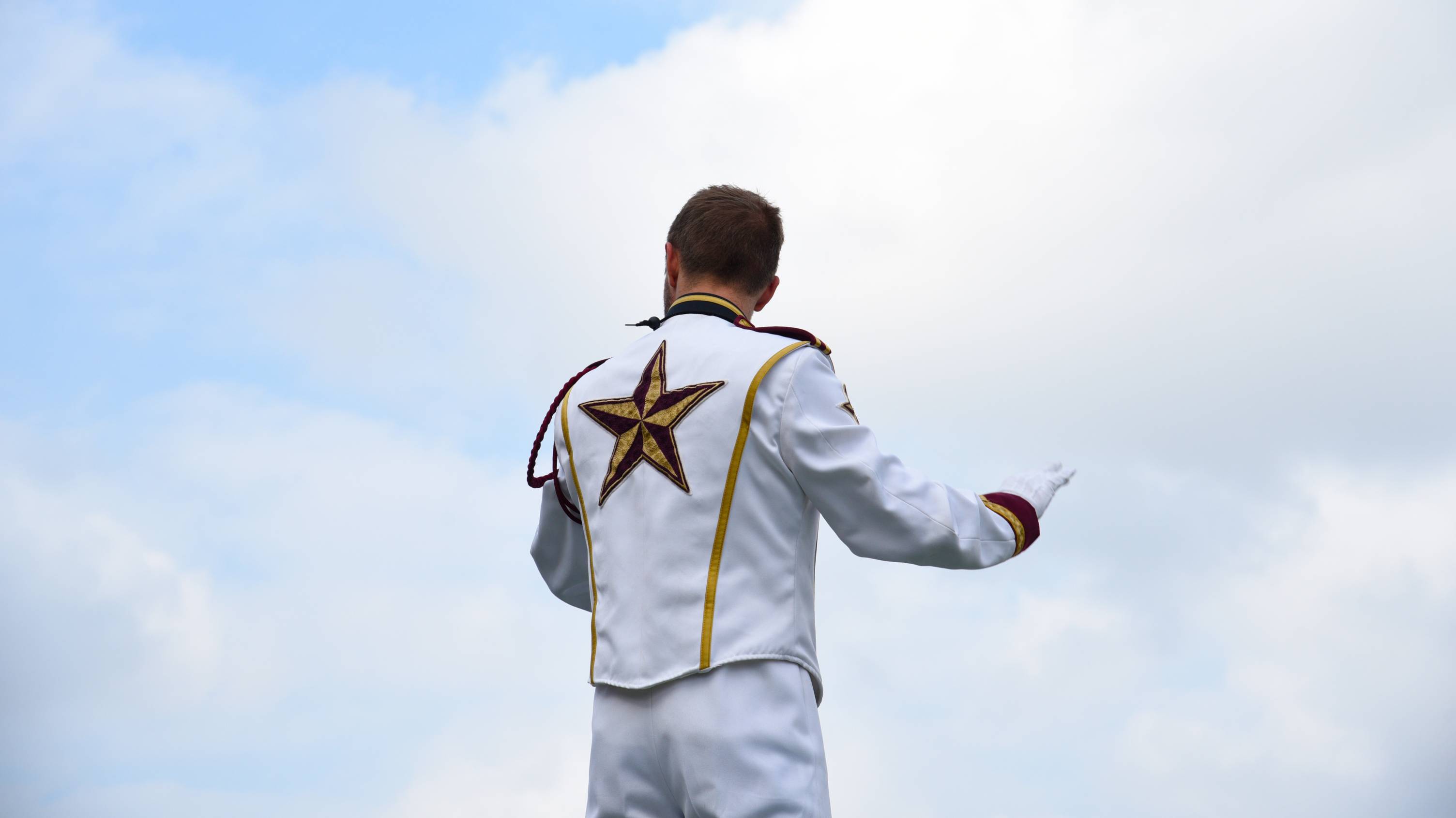 Drum major conducting in front of a cloud.