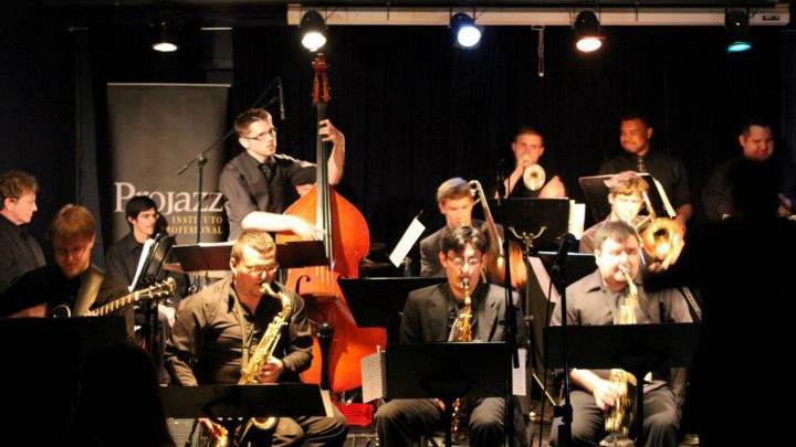 A jazz ensemble performing on a dark stage.