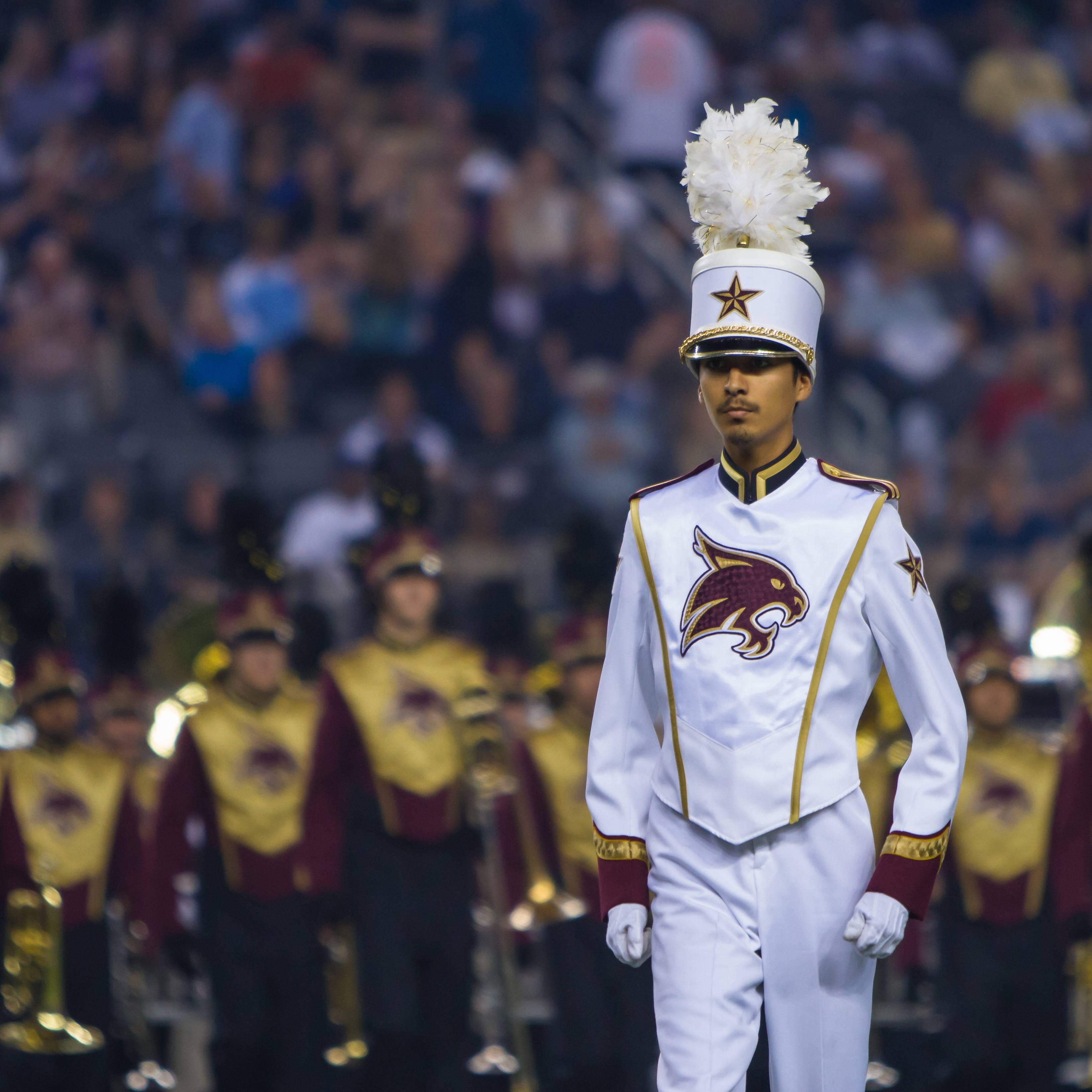 Drum major standing in front of band at night.