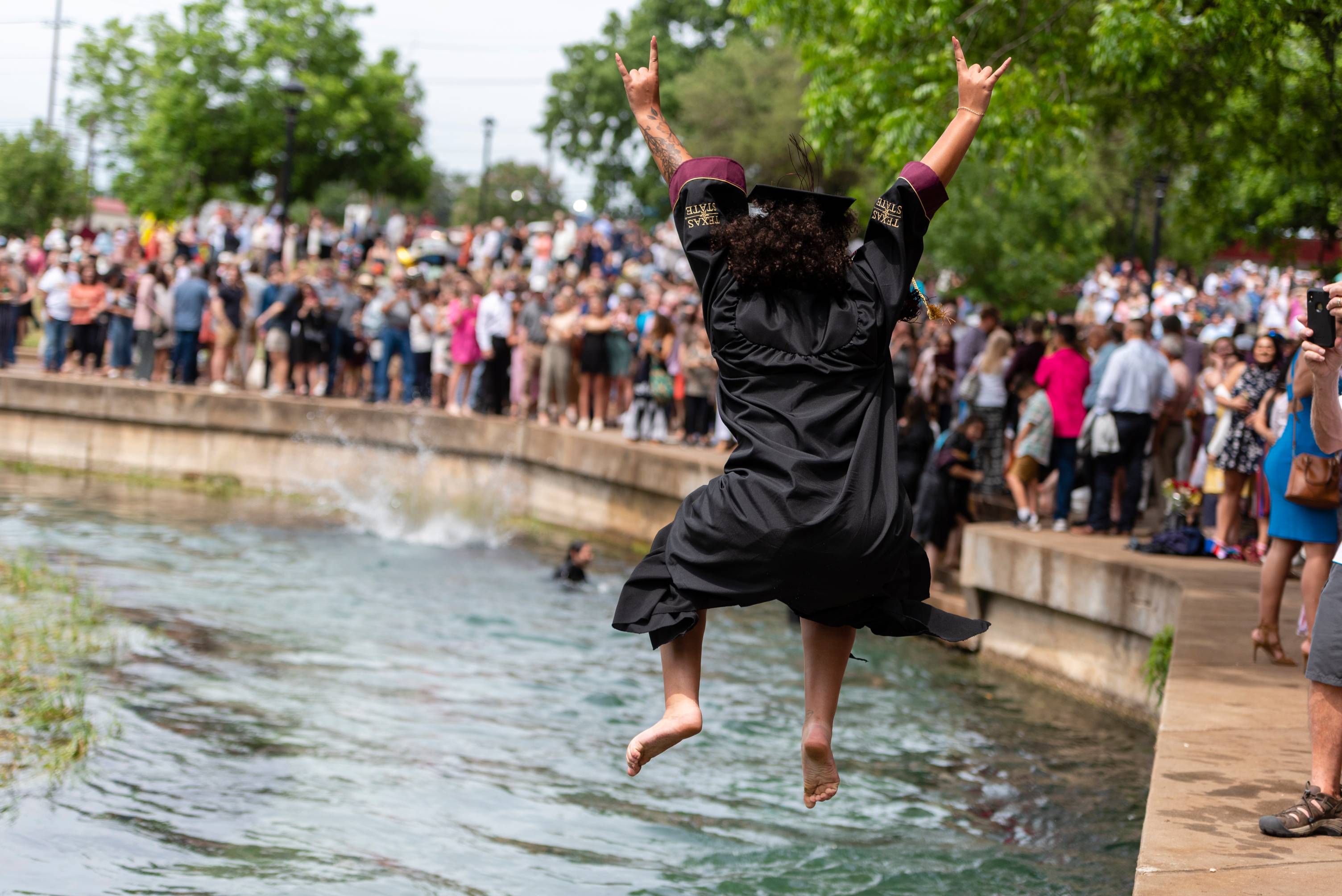 student jumping into the river after graduation