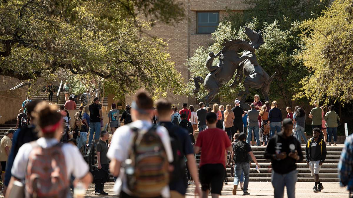 Crowd of students walking around The Stallions statue.