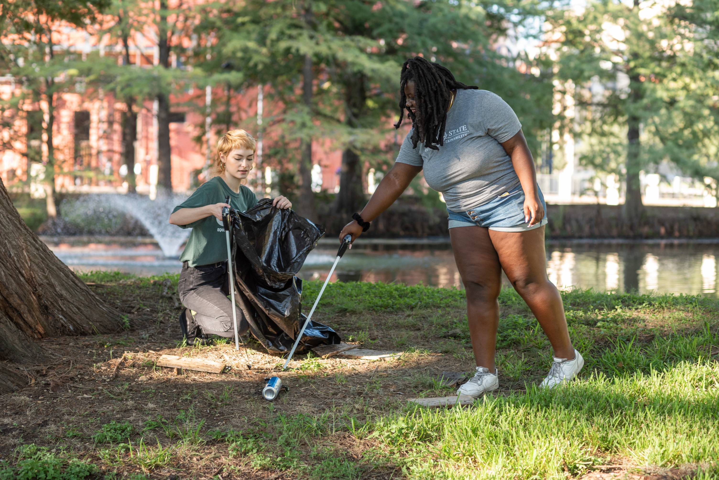 Student holds bags open for another student to place litter in it.