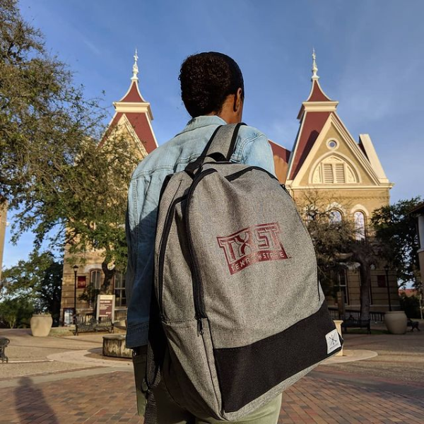 Student in front of Old main with txst backpack