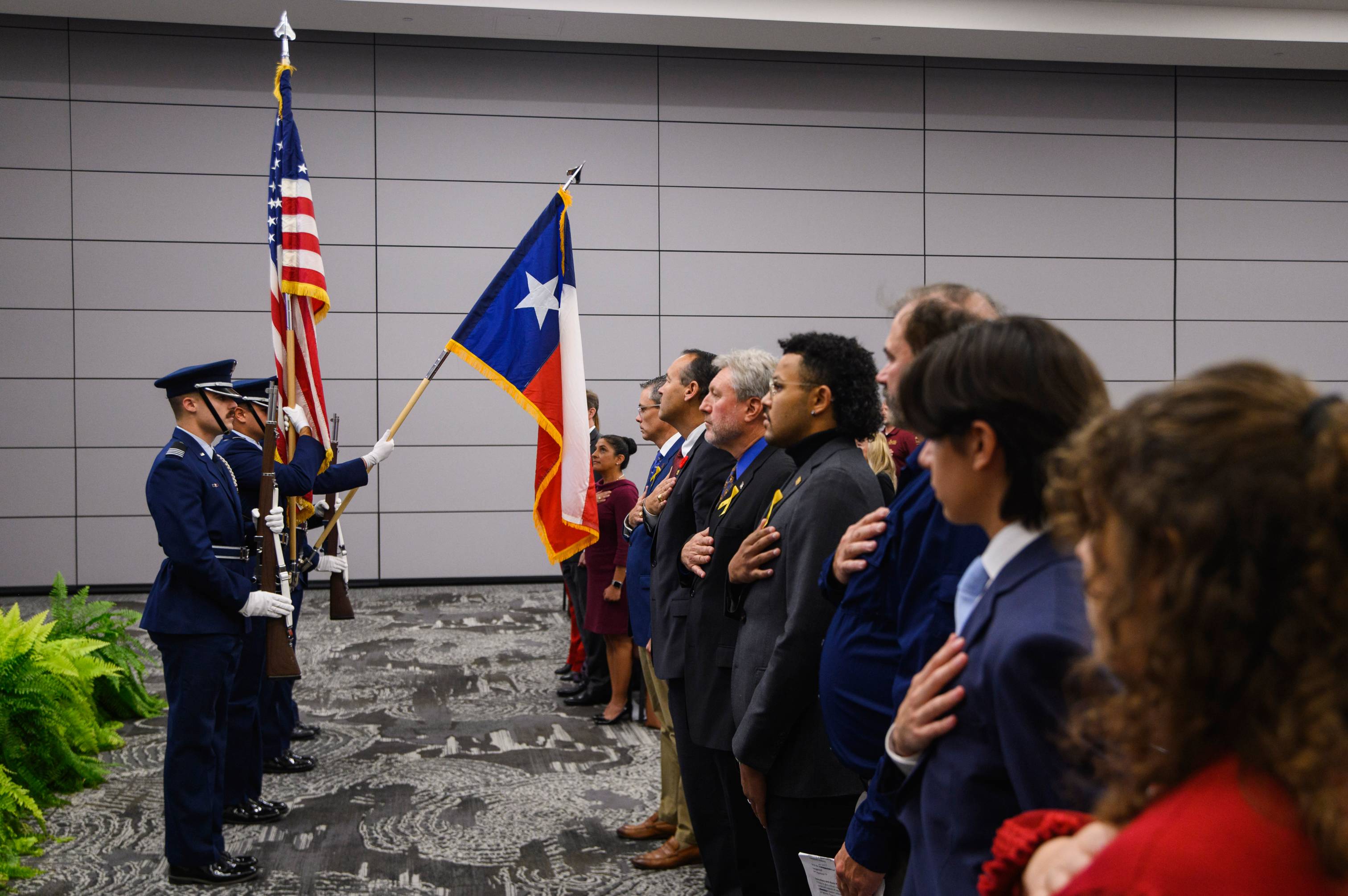 a group says the pledge of allegiance to the texas flag. there is a veteran holding the flag, and there is a U.S. flag in the background.
