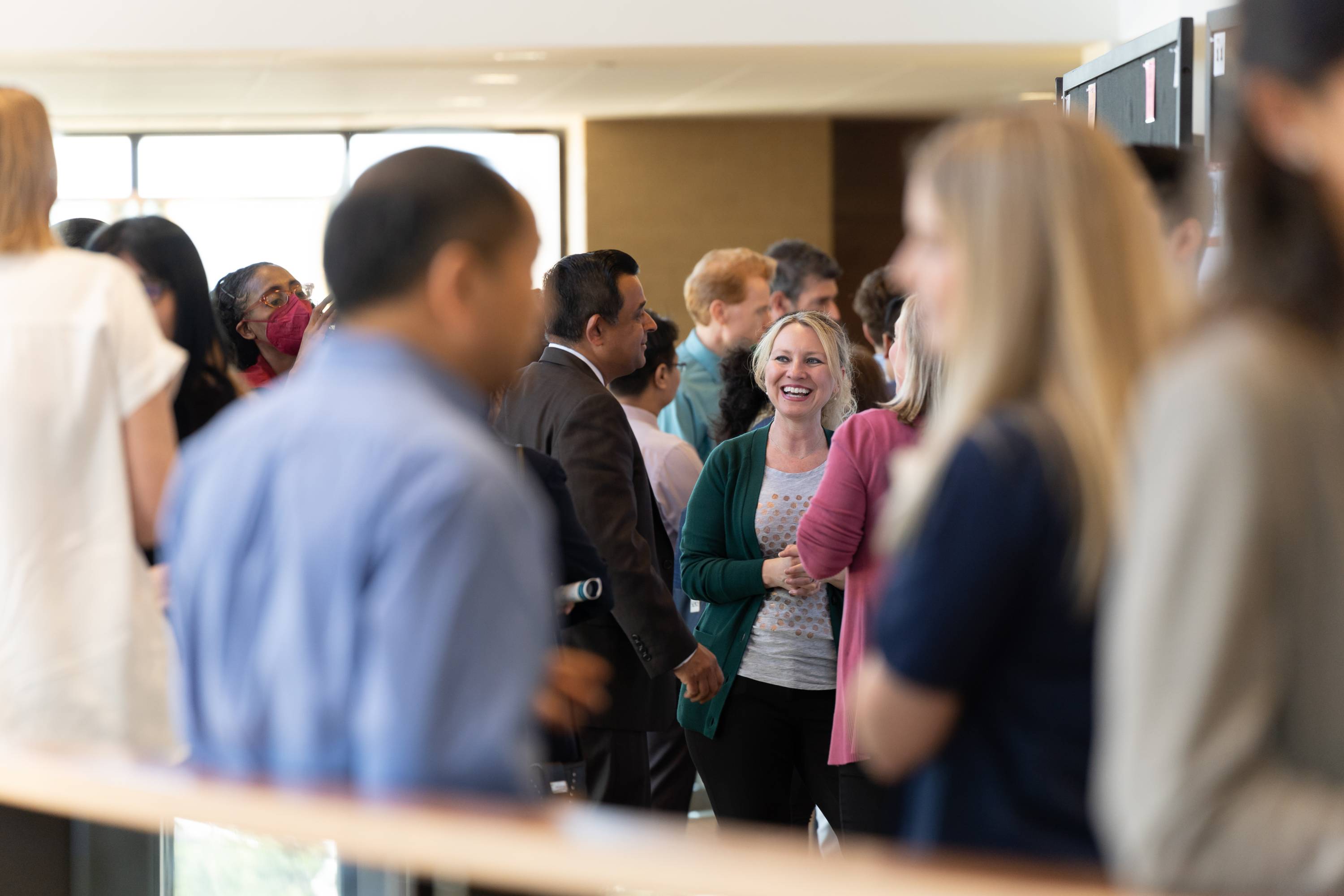 A crowd of people fill up a hall at the Showcase. People are seen talking and laughing in conversation together.