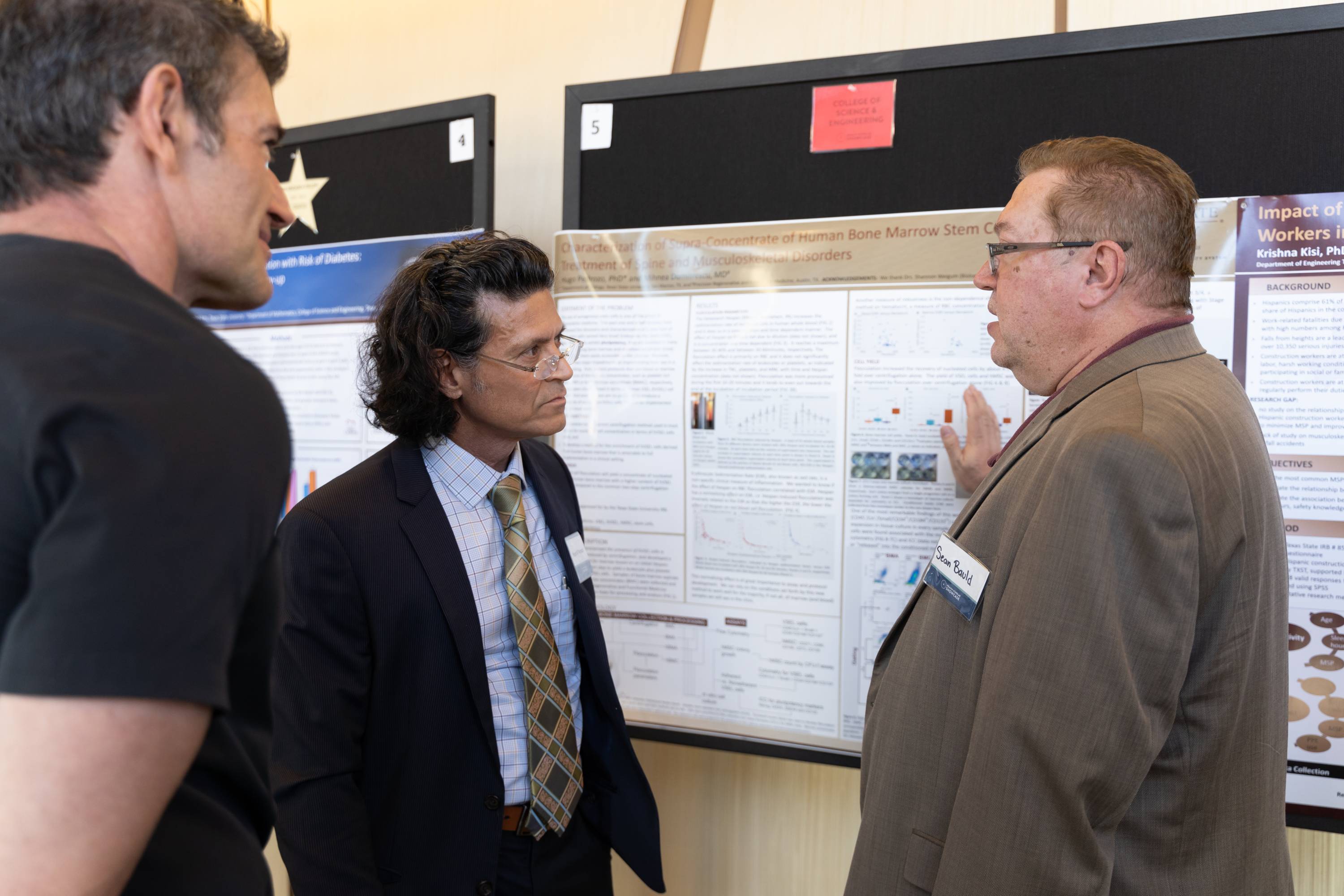 A researcher presents his research poster to two Showcase attendees.