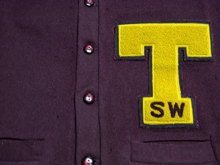 Photograph of Strahan's letter sweater, focusing on the large letter "T" with smaller letters "SW" embroidered at the base.