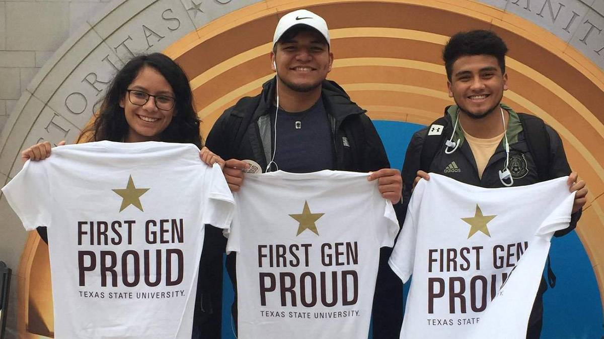 Three students holding up First-Gen Proud t-shirts