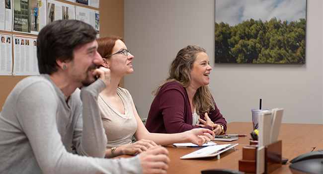 Three office workers sitting around a table and talking