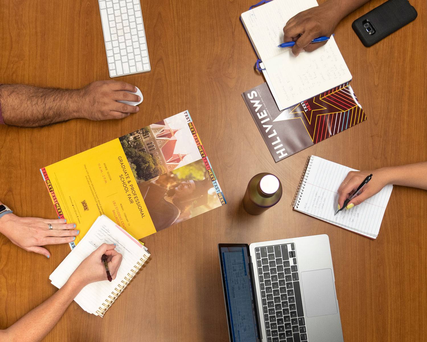 Aerial shot or hands on a table working writing in a notebook and hovering near a laptop