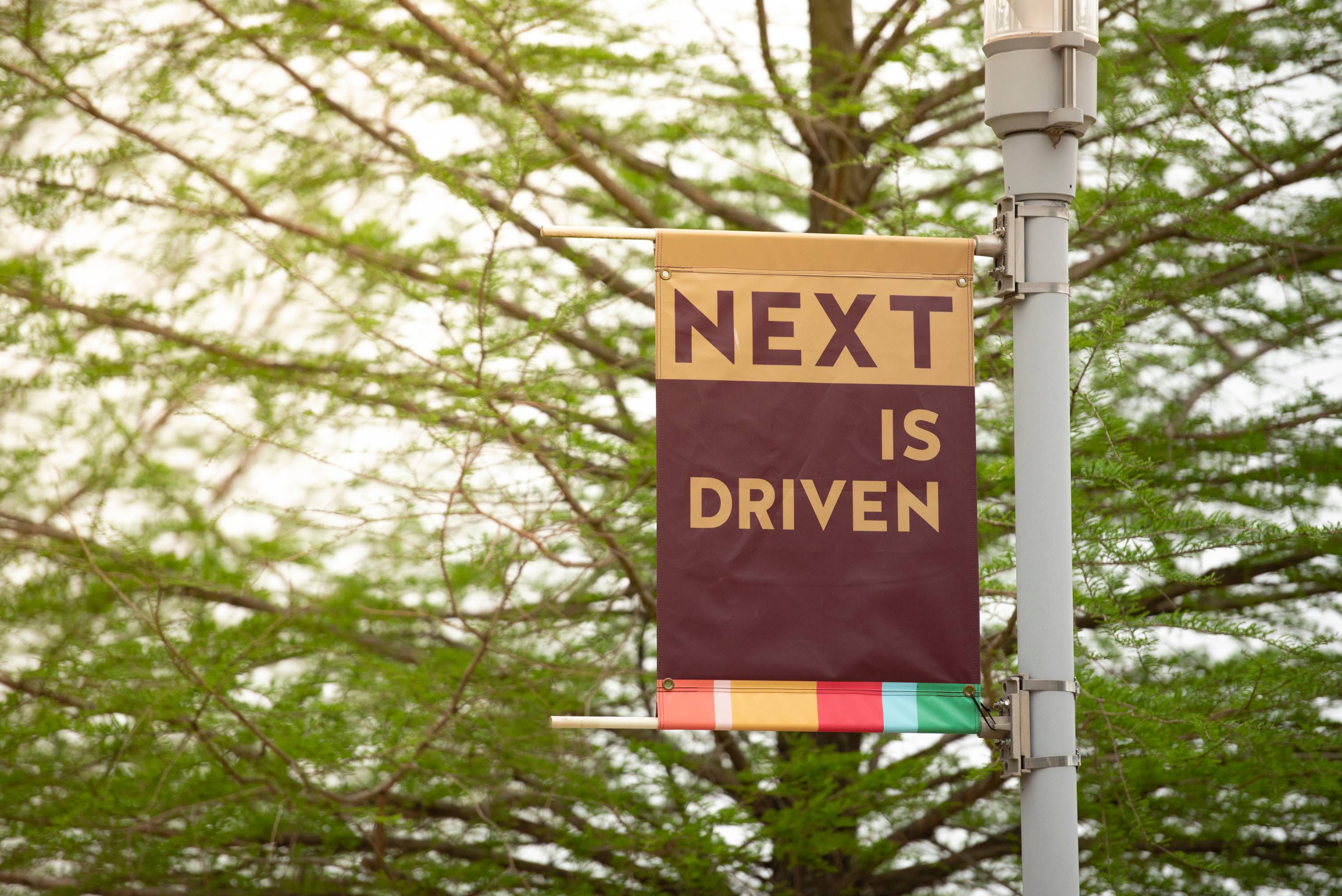 Close up of "Next is driven" light pole banner