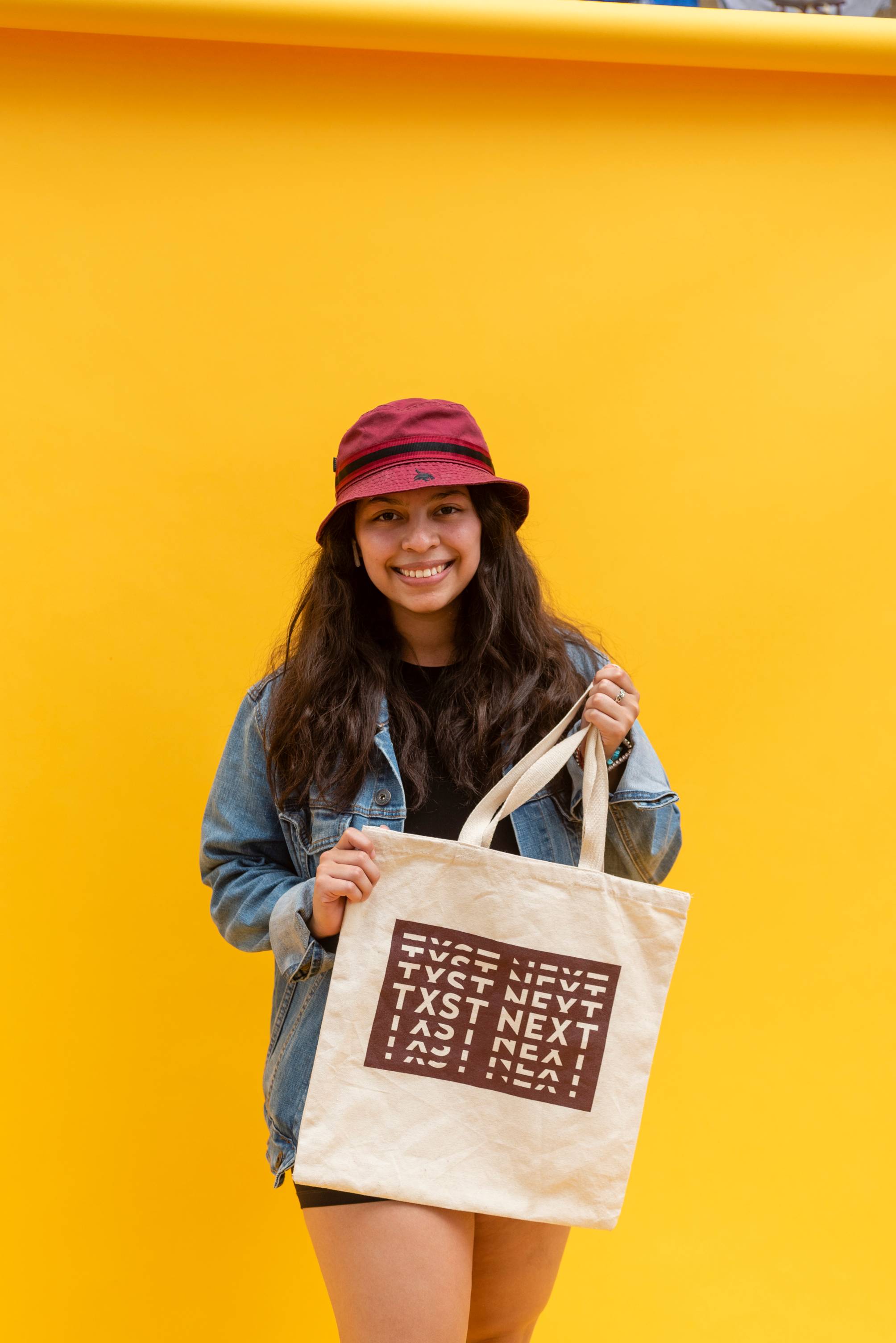 Student displaying their freshly screen printed tote in front of a yellow background