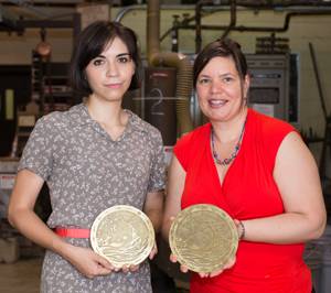 Mabel Sirup (left) and Andrea Weissenbuehler receive bronze medallions depicting their manhole cover design.