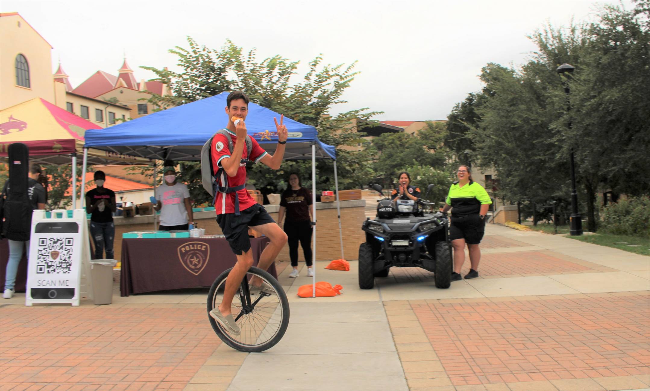 Student on Unicycle eating donut at Coffee with the Cops