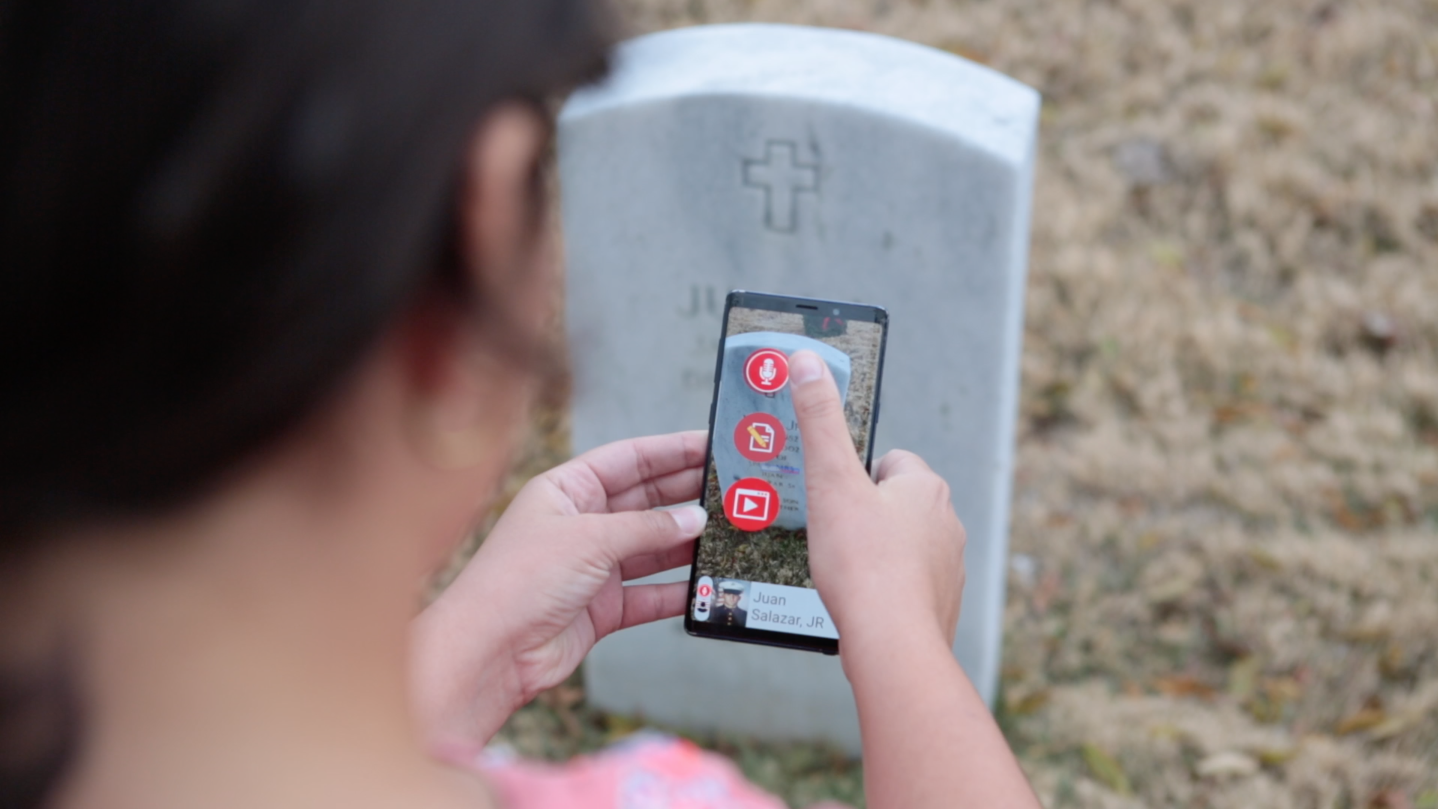 Person adding a story on a cell phone at a grave site