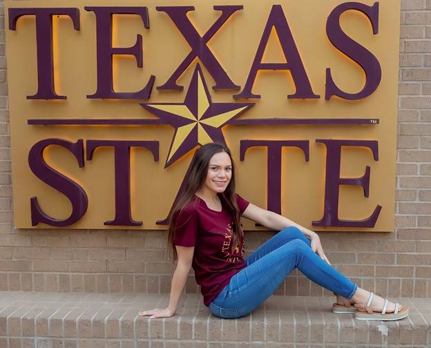 Clarice Kocinn, a scholarship recipient, in front of a Texas State sign