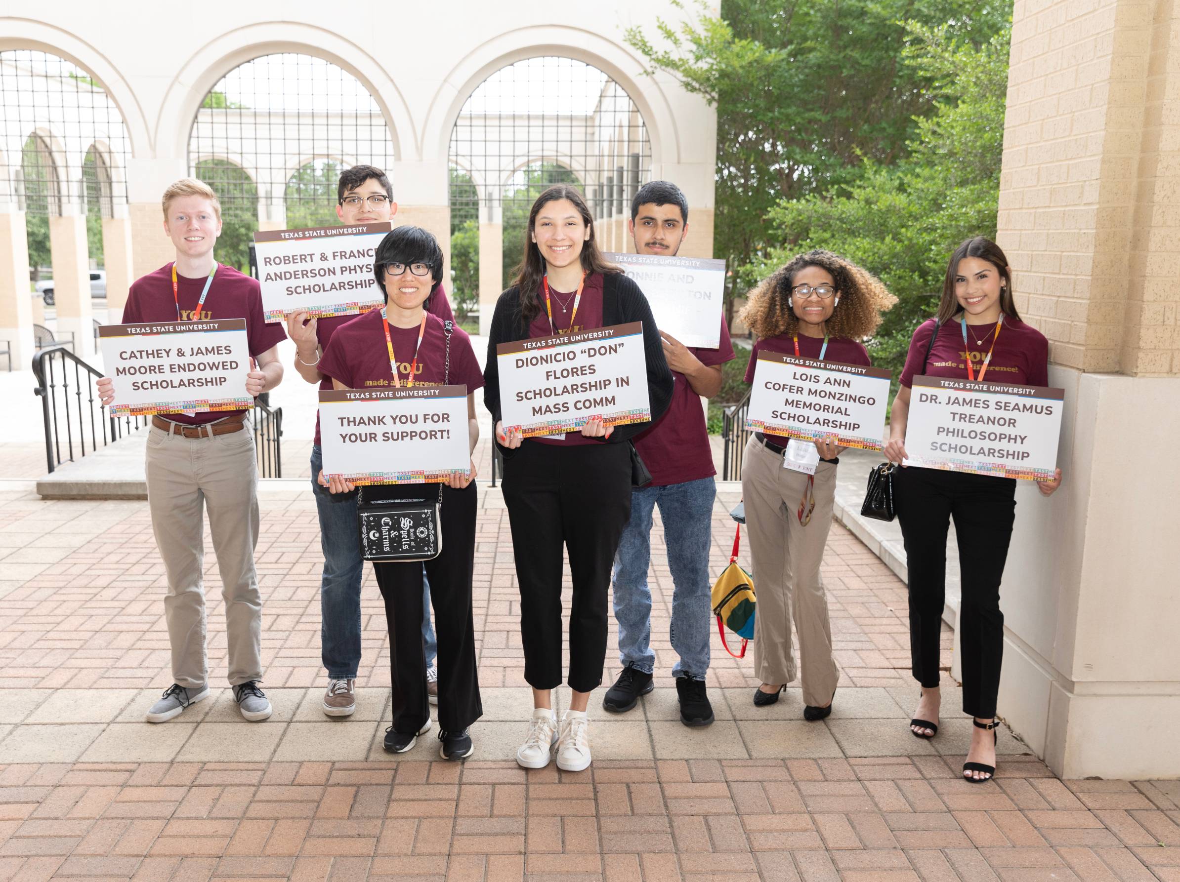 students holding named scholarship signs