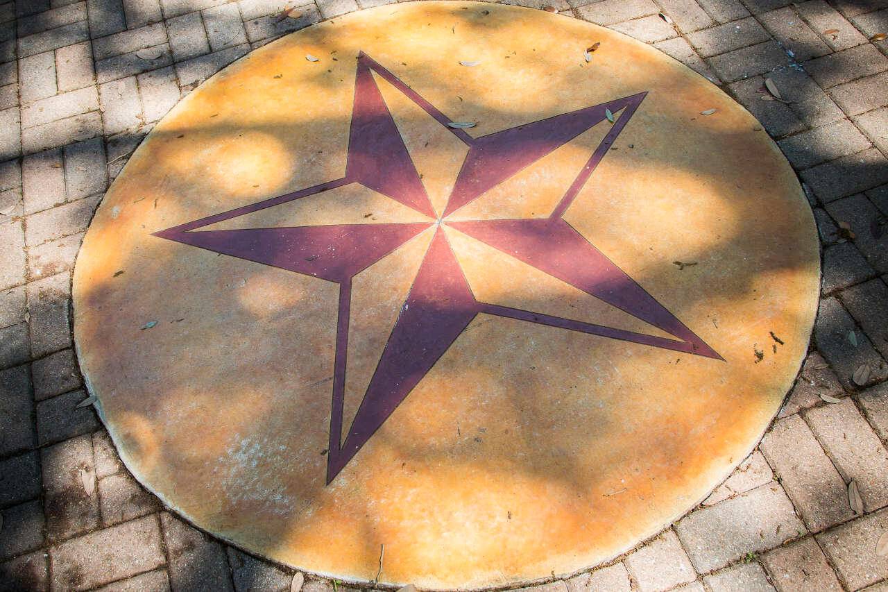 Maroon Texas State star on ground set inside round gold disc