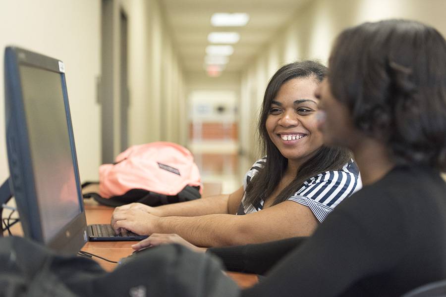 Two people smiling and looking at a computer