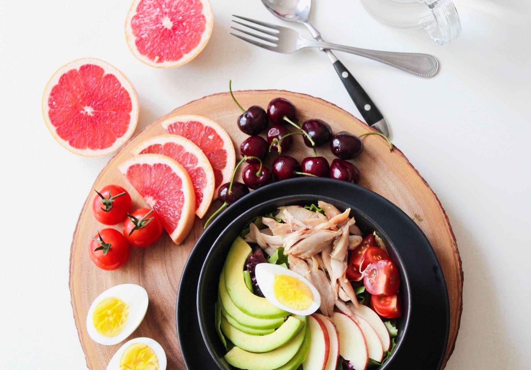 a bowl of chicken, fresh fruits, and vegetables