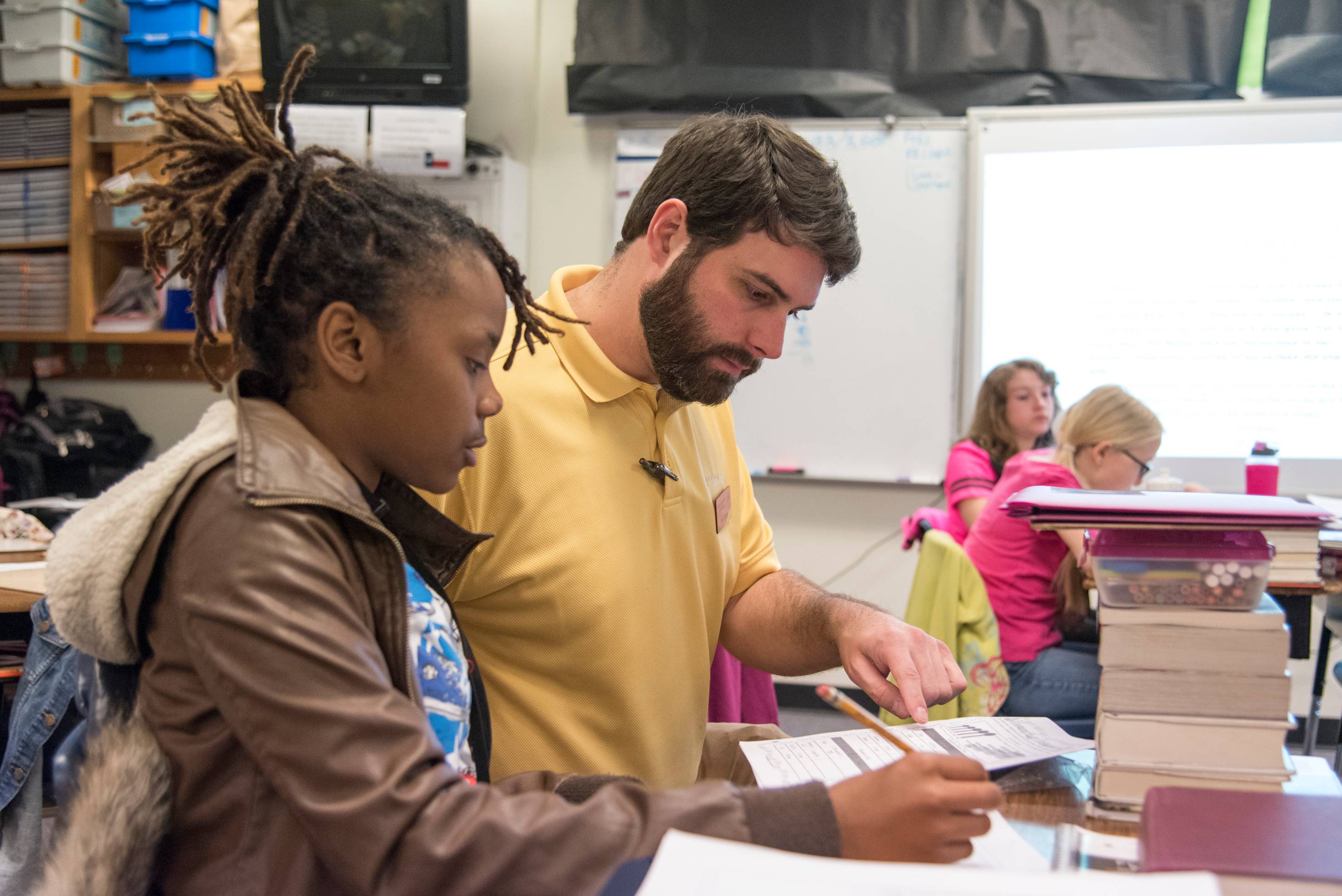 Teacher sitting at desk working with young student