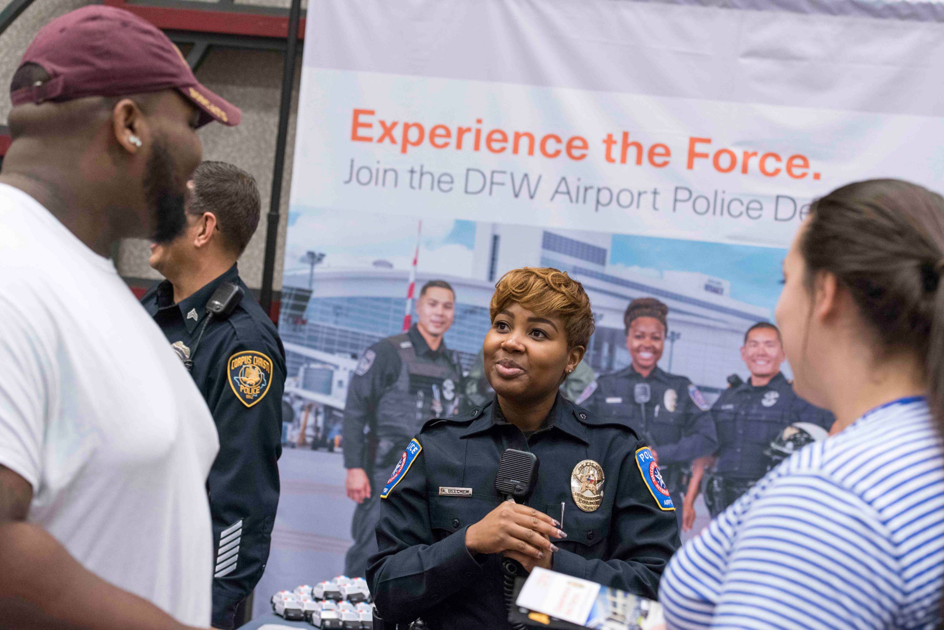 a black female police offer talks with two students at a career fair