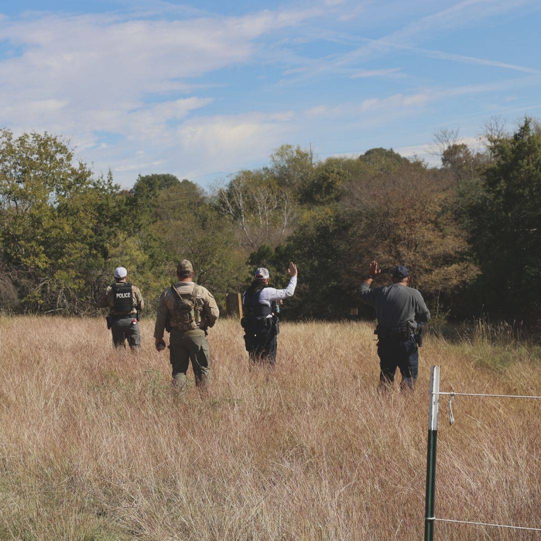 first responders with their backs to the camera walk through a field during an active shooter training