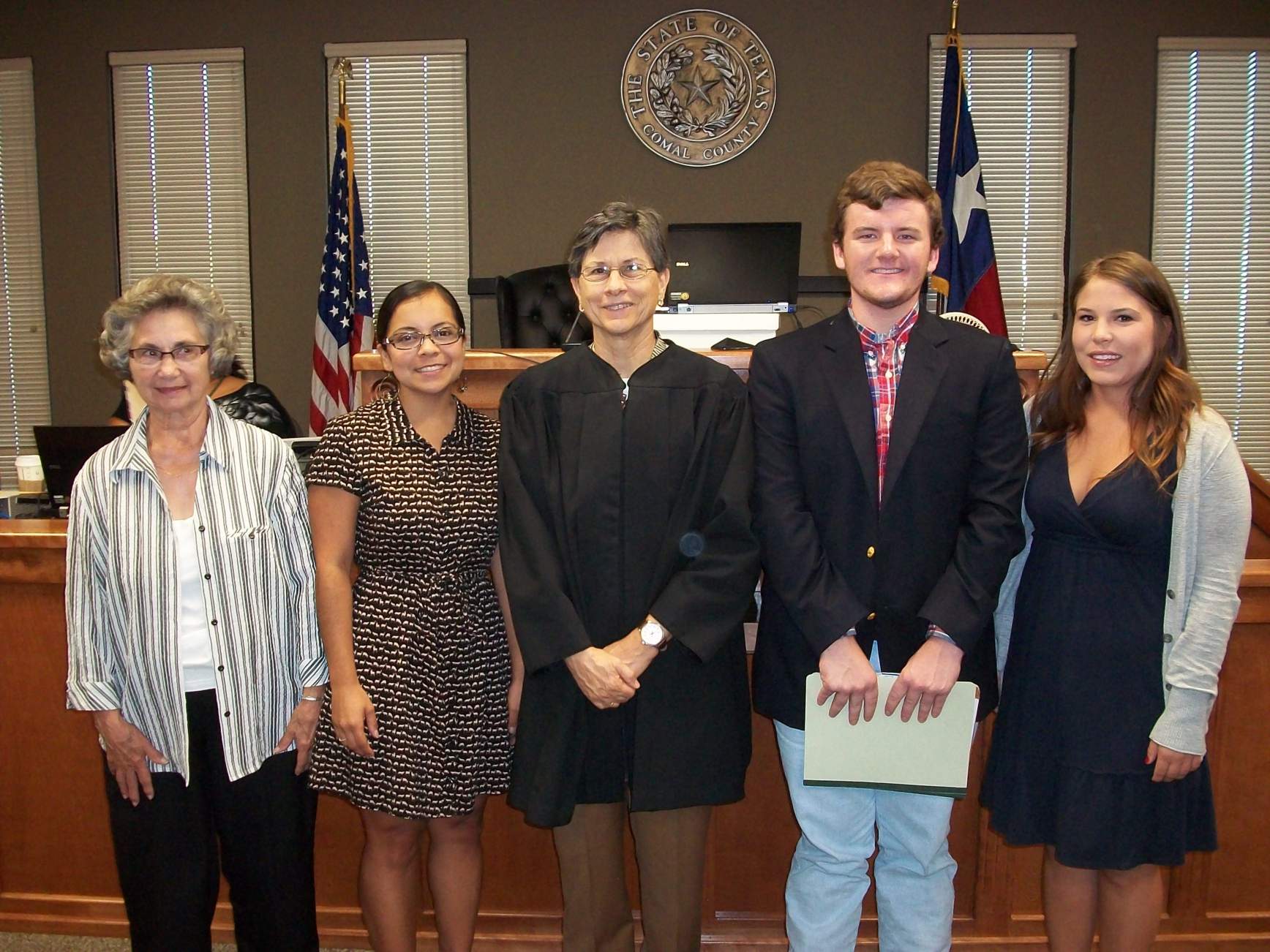 a judge and four CASA advocates pose in a courtroom after a swearing in ceremony