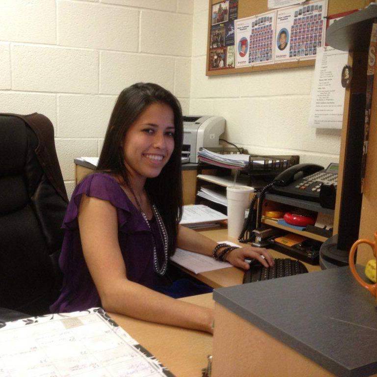 Chantel R. sits at a desk and smiles at the camera
