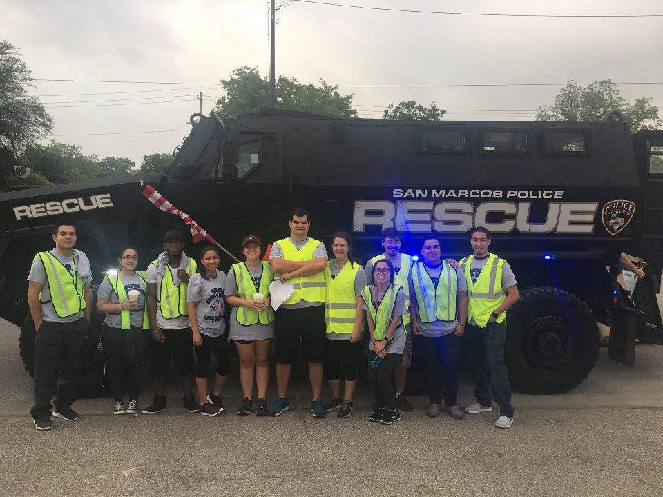 student who are members of a criminal justice student organization pose for a picture in front of an emergency rescue vehicle