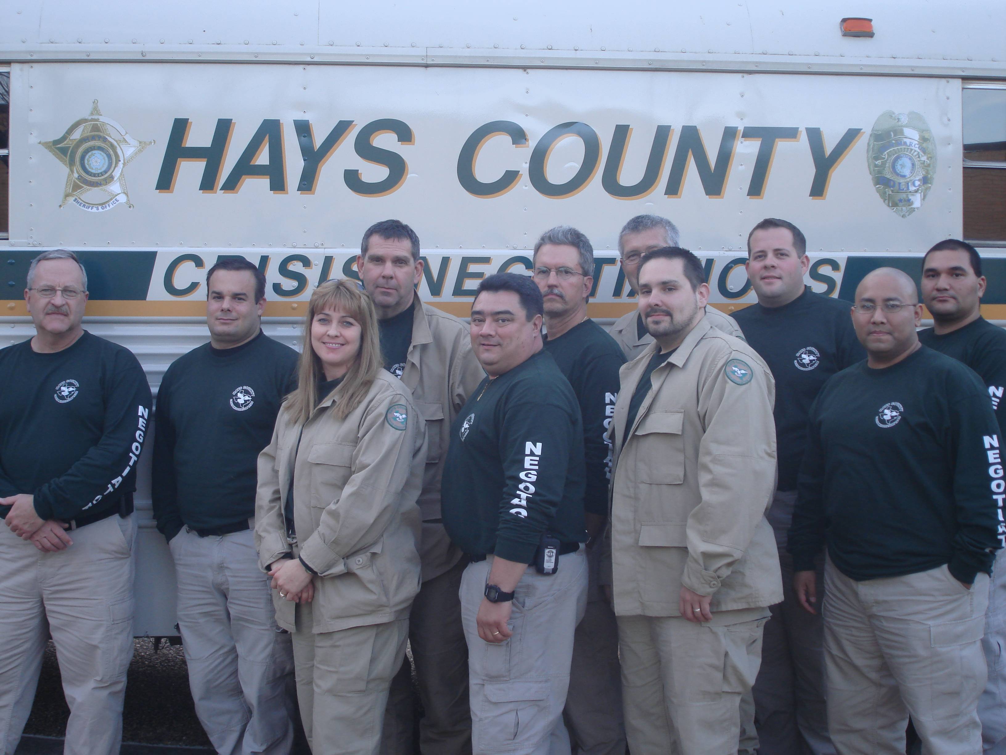 a group of event participants pose in front of a Hays Country banner