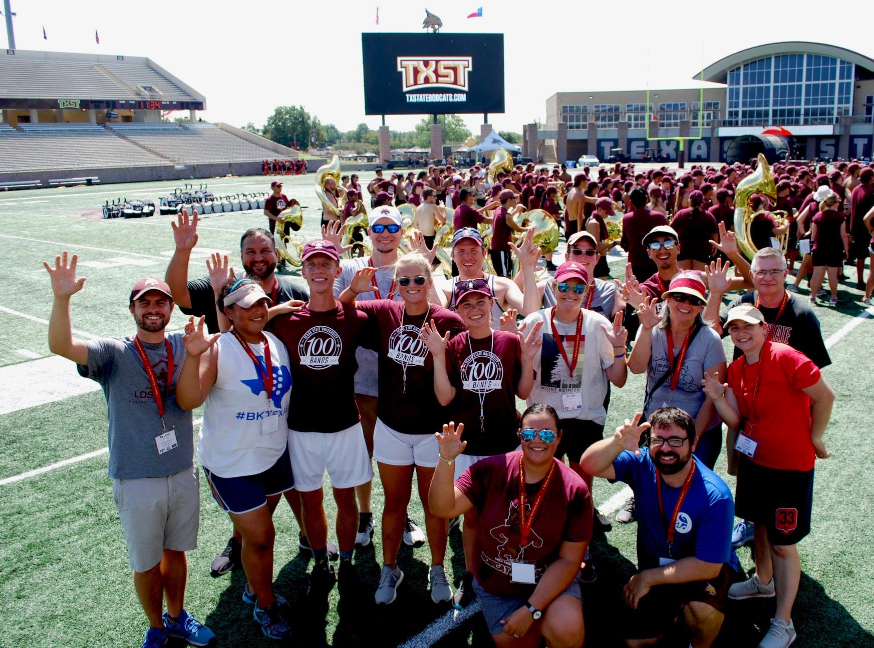 A group of former BMB Drum Majors standing on the practice field