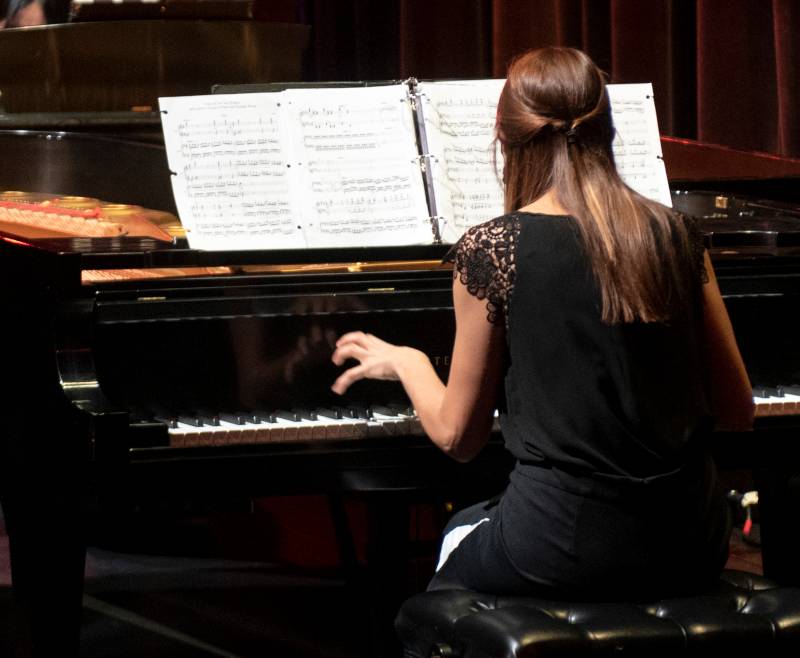 A picture of a student playing a musical composition on the piano.