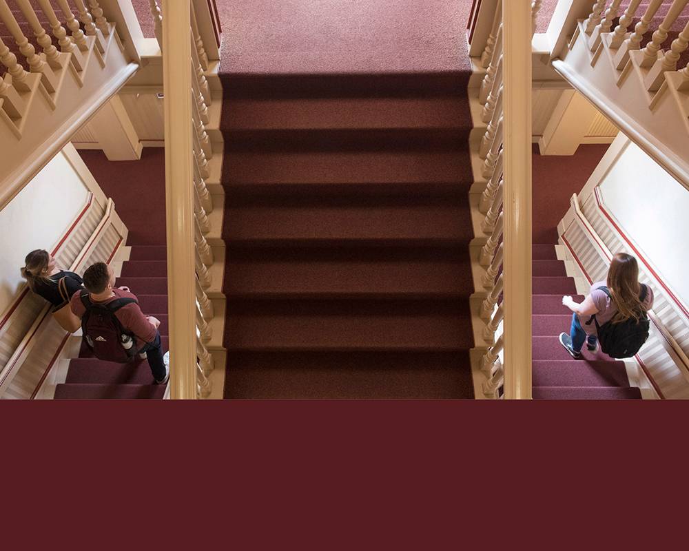 Maroon stairs in Old Main against stripe of maroon brand color