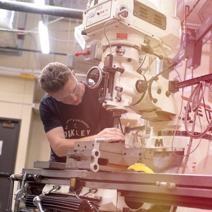 An engineering student works on a machine