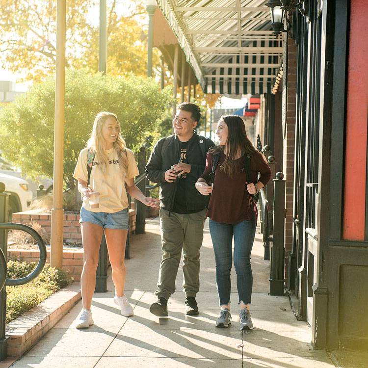 Three students stroll the San Marcos square