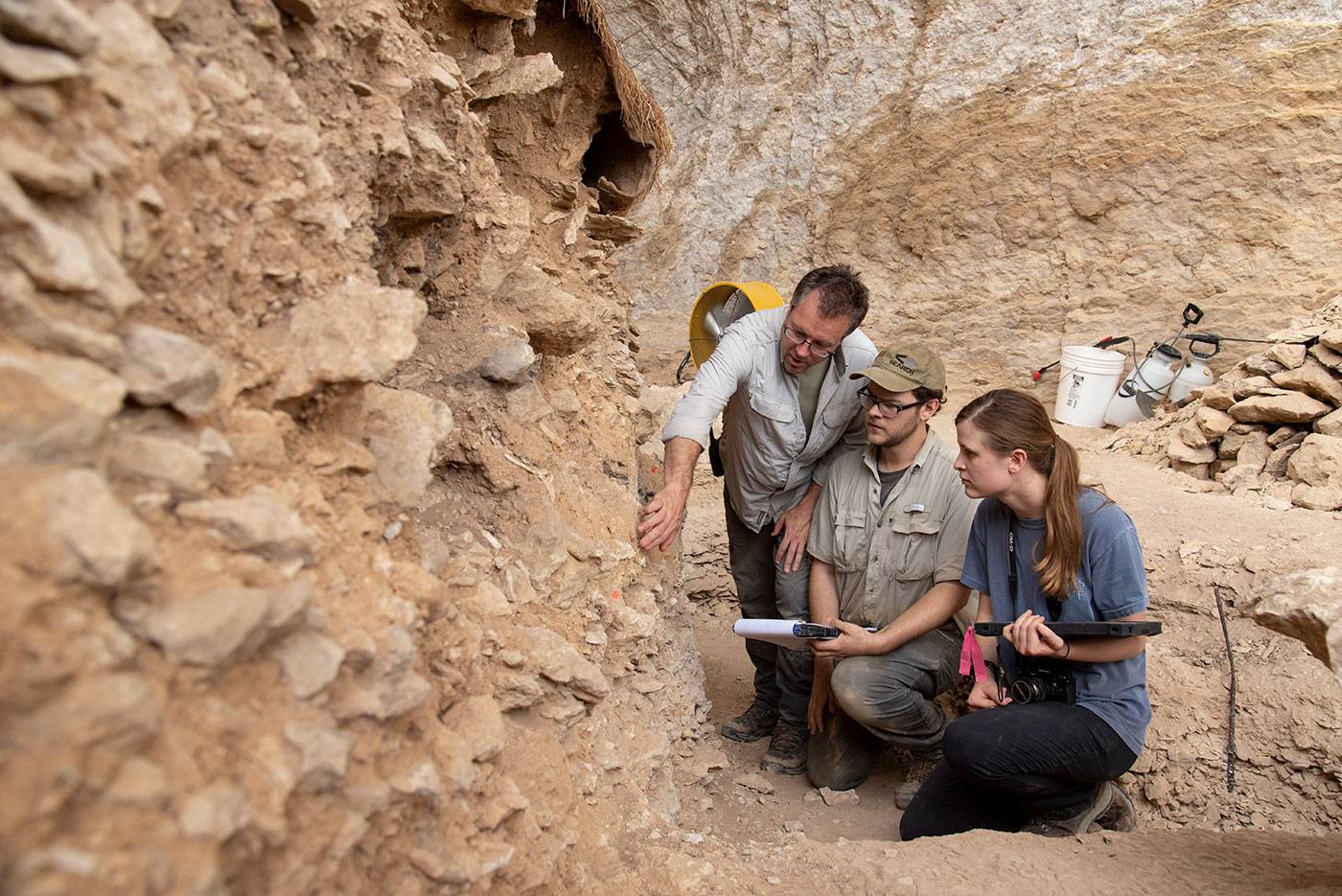 Students working with a professor, studying an ancient bed rock.