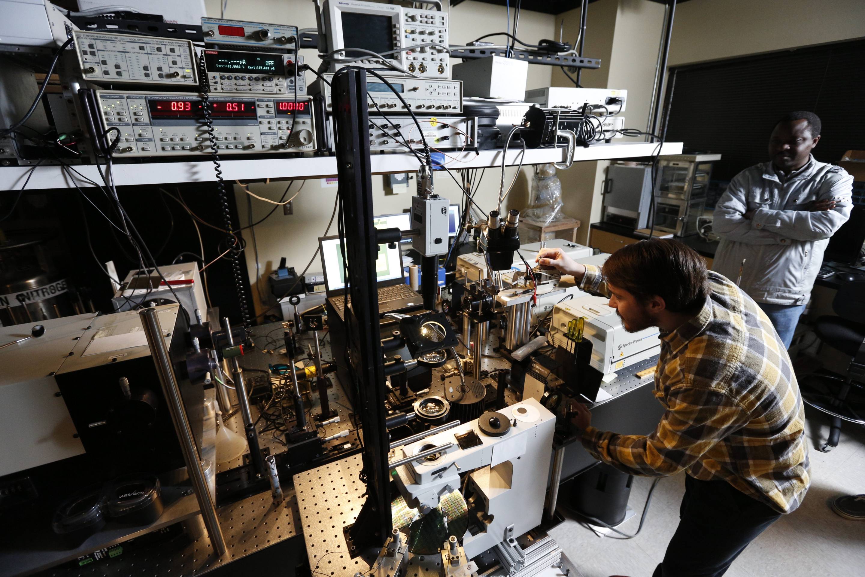 Two TXST individuals inspect a laser