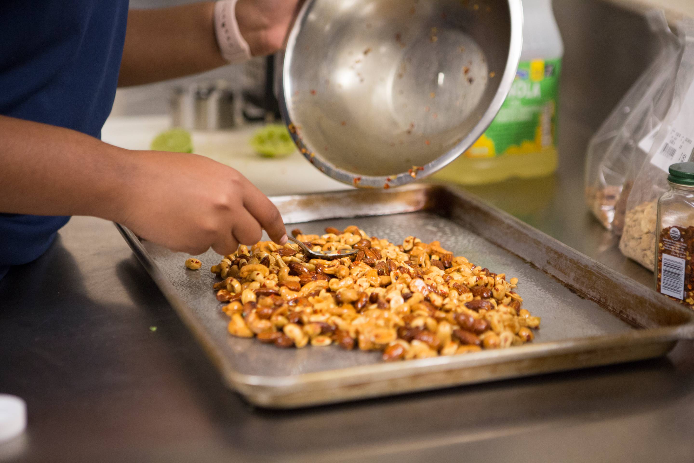 TXST member spreads assorted nuts out on a pan