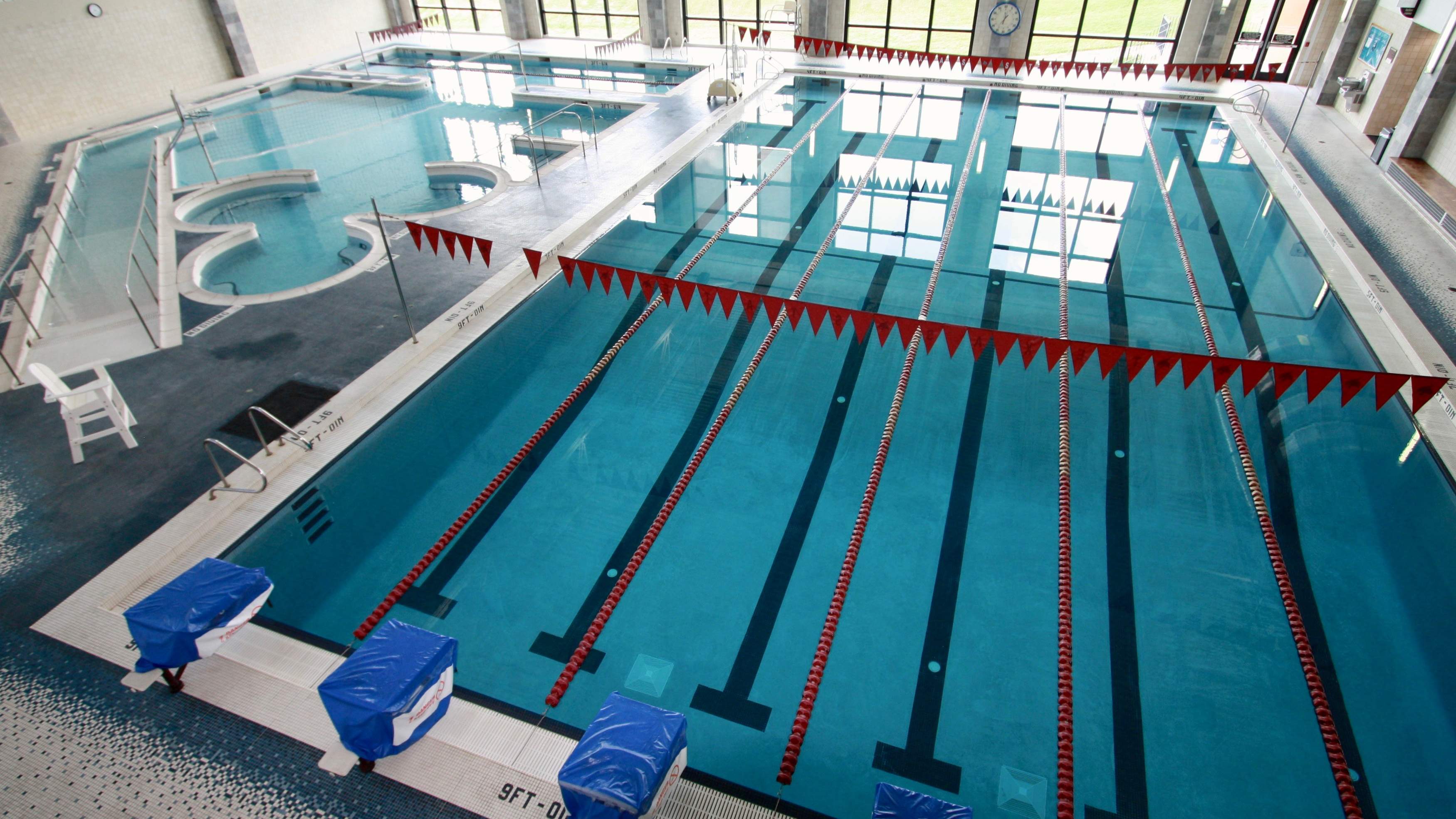 Photo of lap pool with six lanes that are 25 yards in length. Lane lines are marron and white and backstroke flags have TXST logos