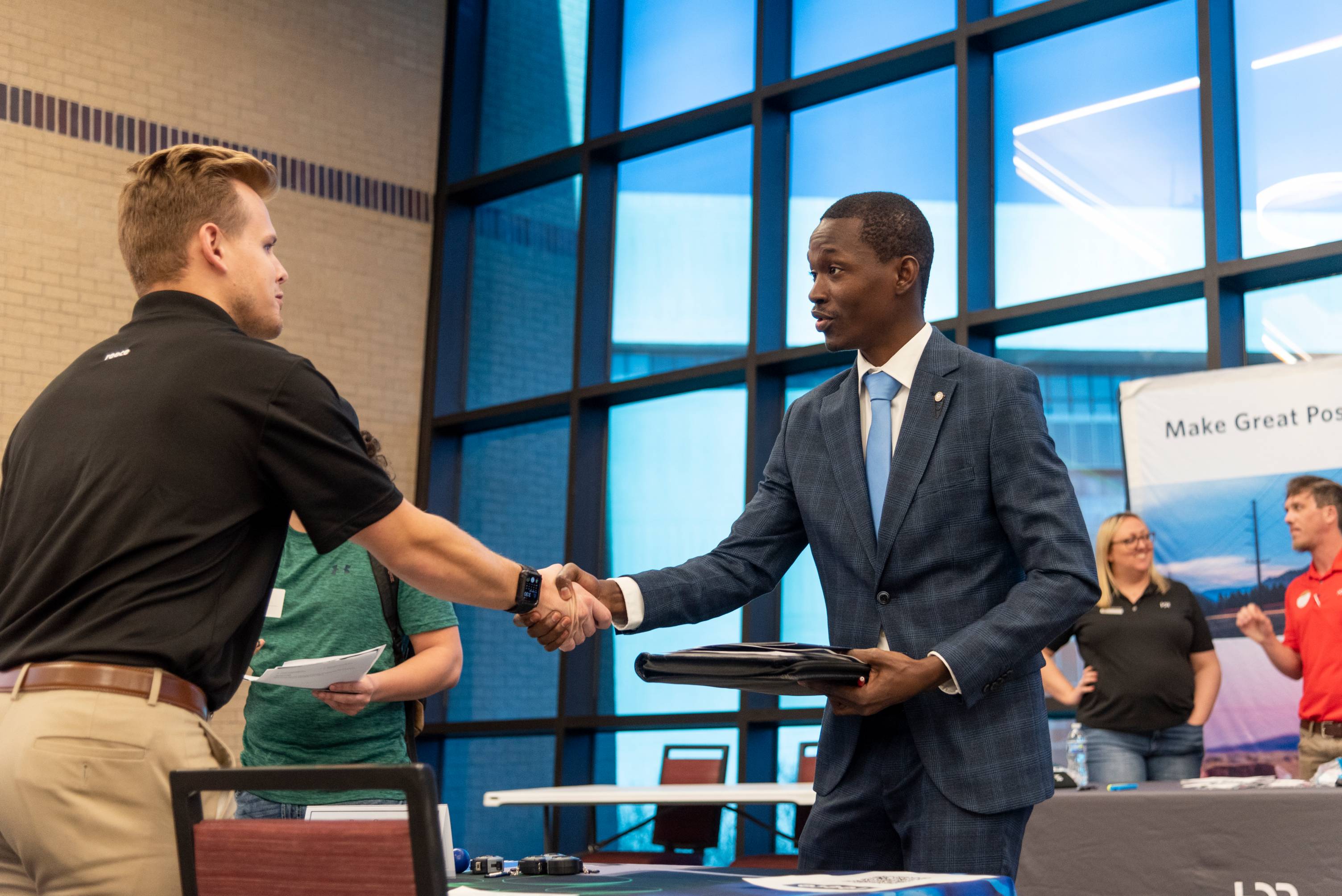 Student dressed sharply in a suit shakes hands with a recruiter at a Texas State Career fair