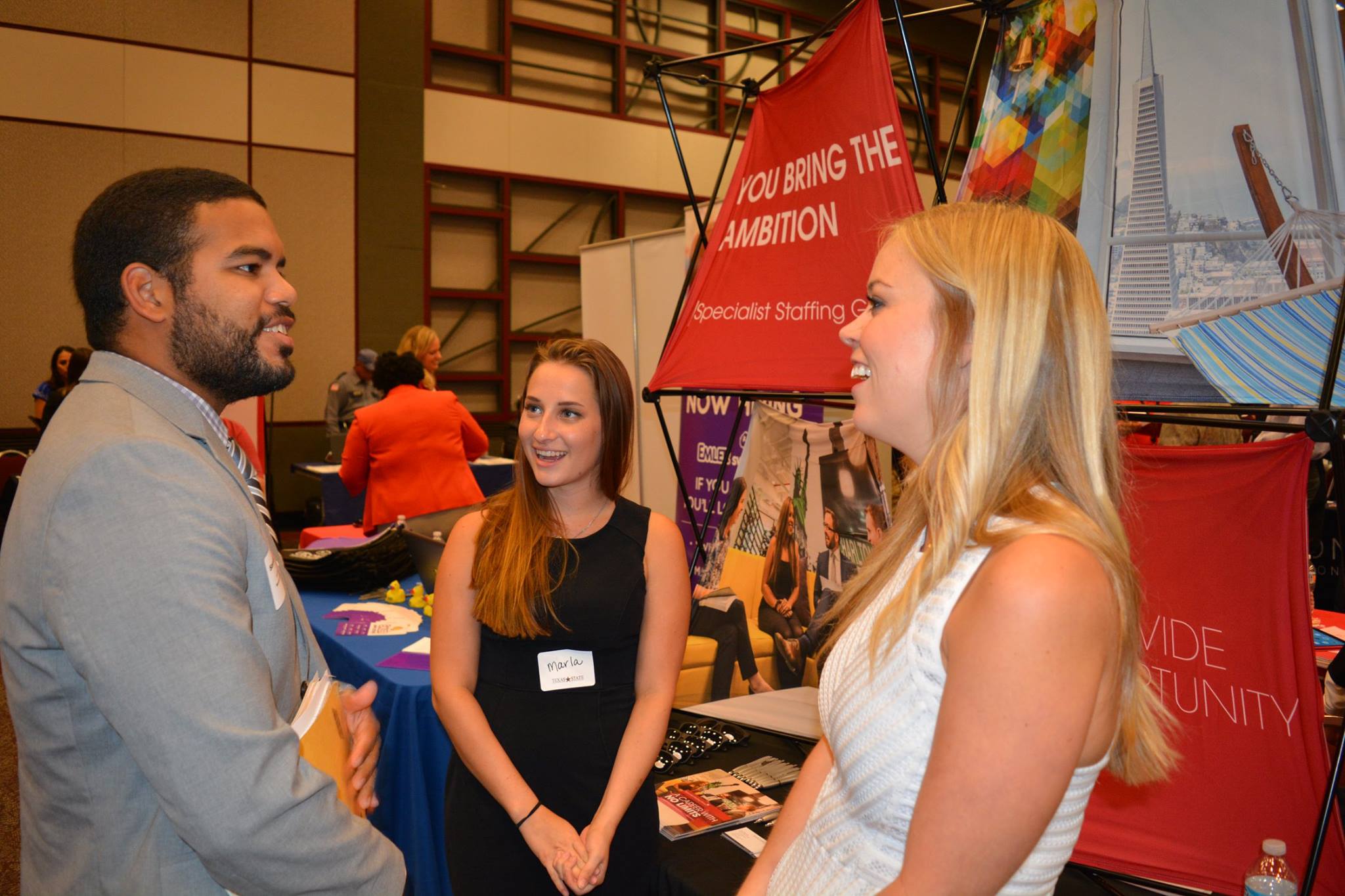A student job seeking speaking to two recruiters at a career fair booth