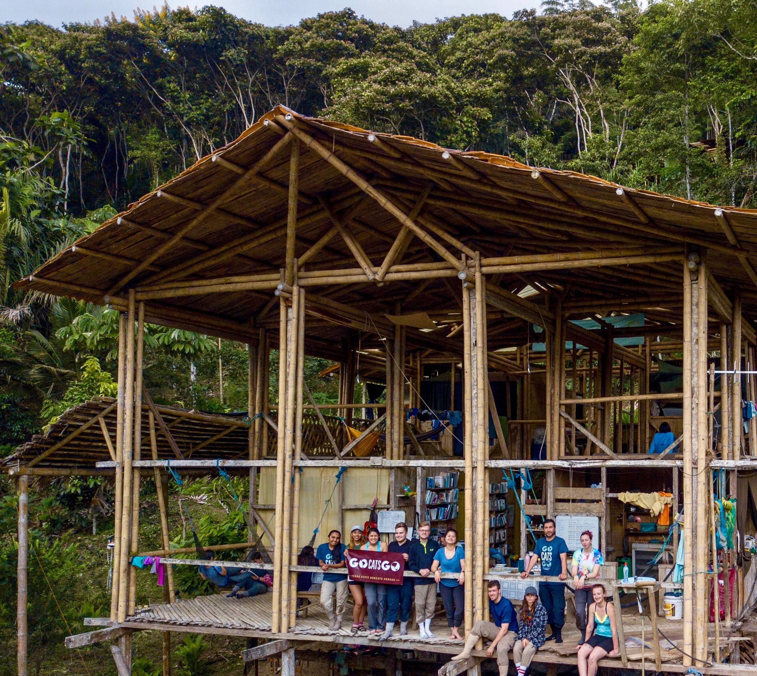 Students holding banner 'New classroom' in the jungle 