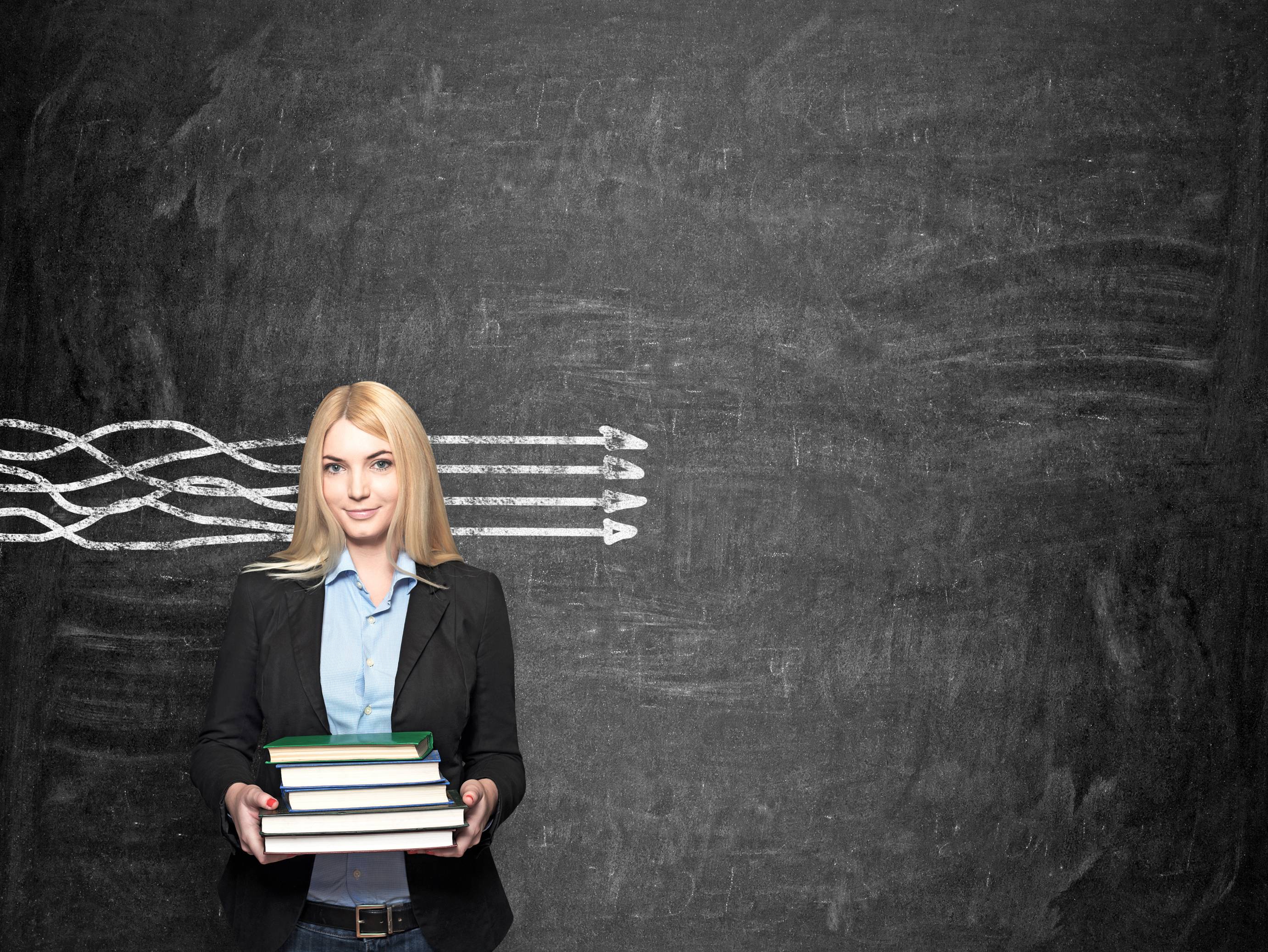 Person carrying books with parallel arrows on chalk board behind them.