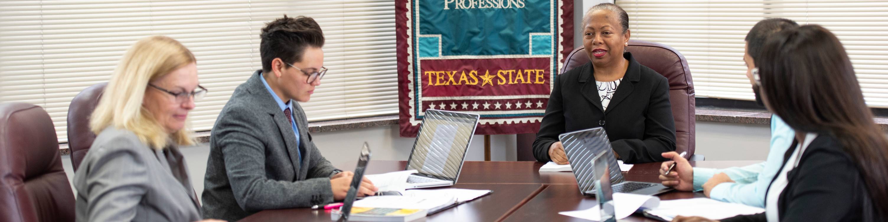 Dr. Ramamonjiarivelo sitting with students at a table.