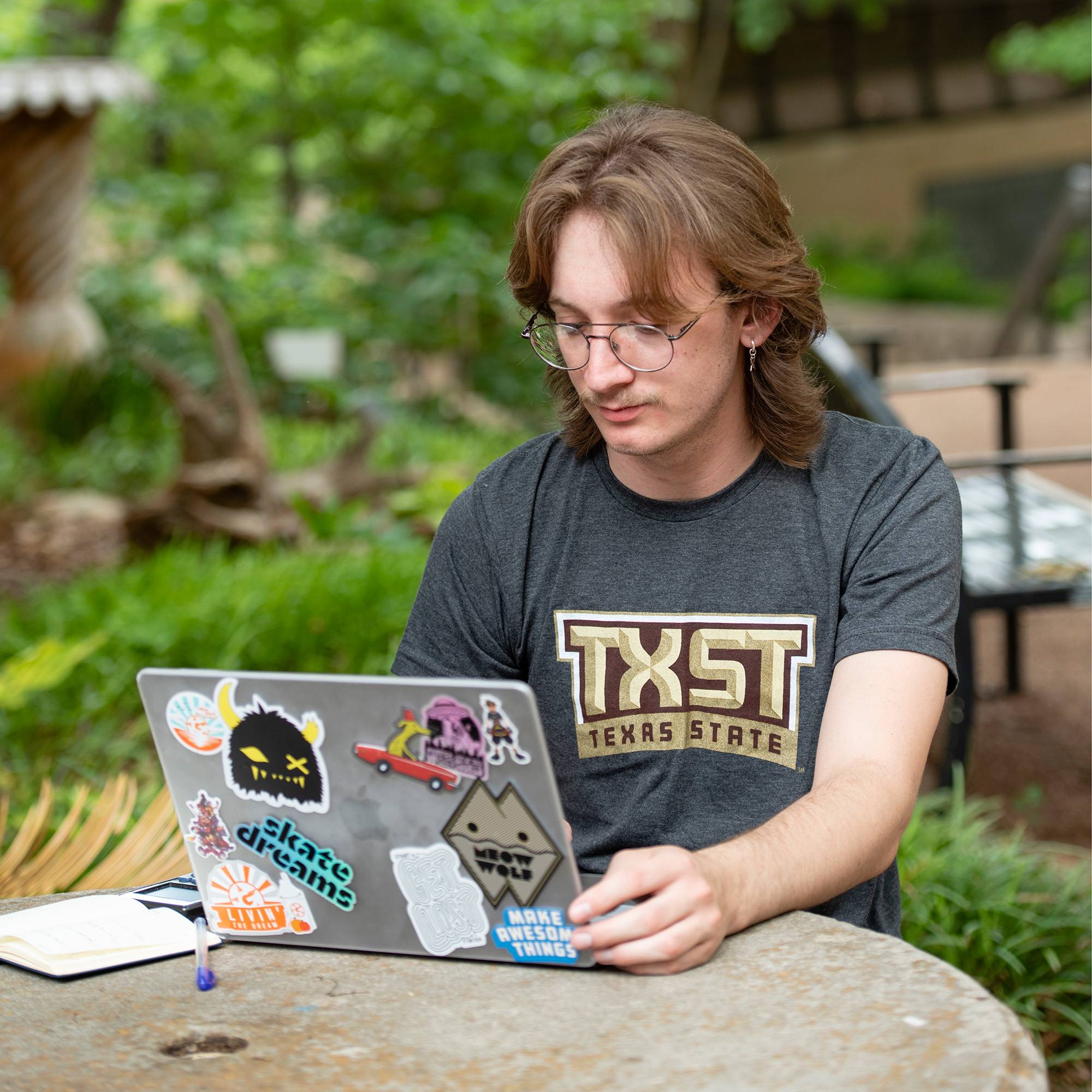 Student with Texas State shirt on computer