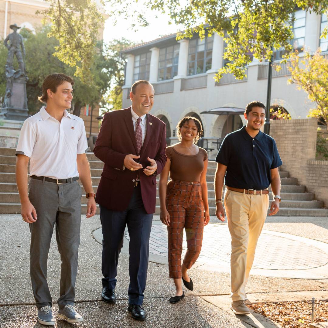 President with students in front of Lampasas Hall