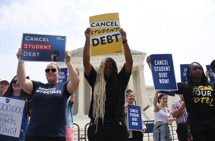 protestors holding signs in support of debt cancellation