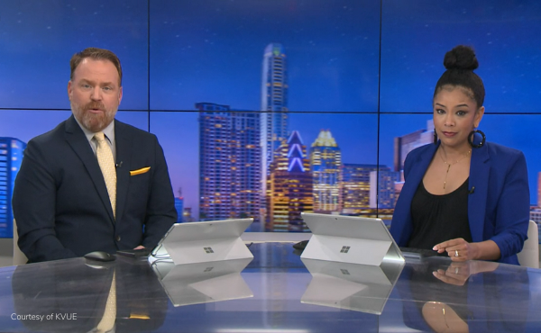 Two news anchors sitting at a desk reporting the news.